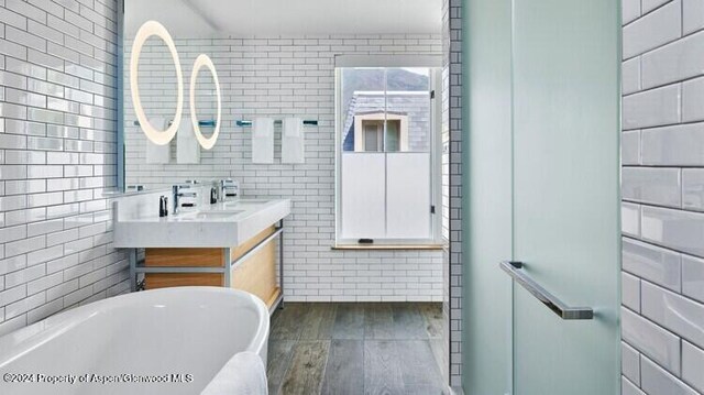 bathroom featuring a bathing tub, vanity, wood-type flooring, and tile walls