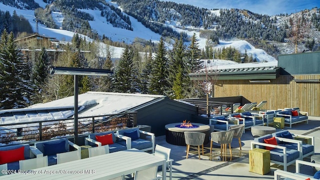 snow covered patio featuring a mountain view and a fire pit