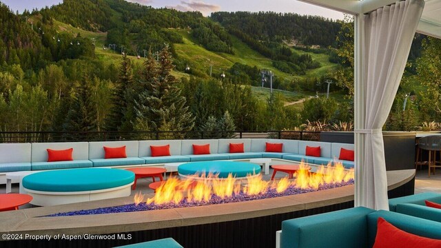 pool at dusk featuring a mountain view and an outdoor living space with a fire pit