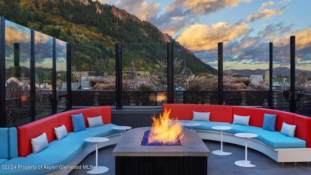 patio terrace at dusk featuring a mountain view and an outdoor living space with a fire pit