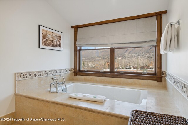 bathroom with tiled bath and vaulted ceiling