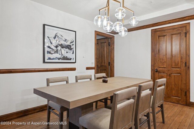 dining space with hardwood / wood-style floors and an inviting chandelier