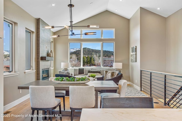 dining room with a chandelier, wood finished floors, a tile fireplace, and baseboards