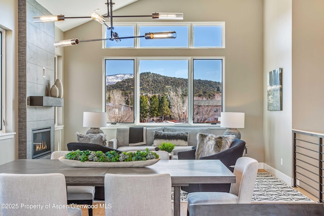 dining space featuring lofted ceiling, a mountain view, a notable chandelier, a fireplace, and baseboards