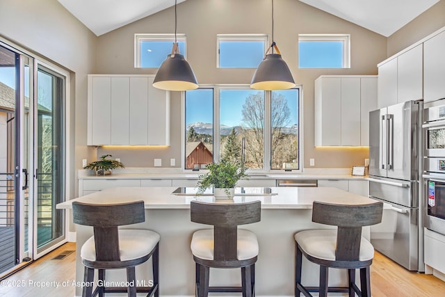 kitchen with stainless steel appliances, a breakfast bar, a kitchen island, and light countertops