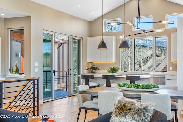 dining room with light wood-type flooring, high vaulted ceiling, and recessed lighting