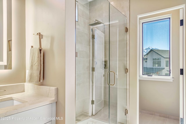 full bathroom with a stall shower, tile patterned flooring, vanity, and baseboards