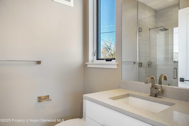 bathroom with a stall shower, vanity, and toilet