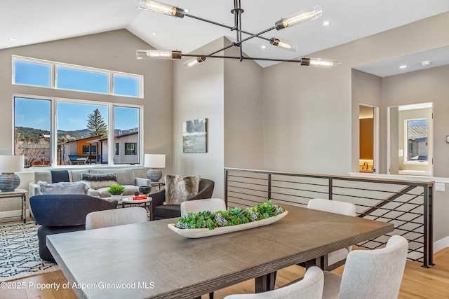 dining space with light wood-style floors, high vaulted ceiling, and an inviting chandelier