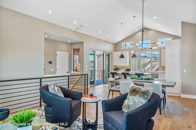 living room with light wood-type flooring, visible vents, high vaulted ceiling, and a notable chandelier