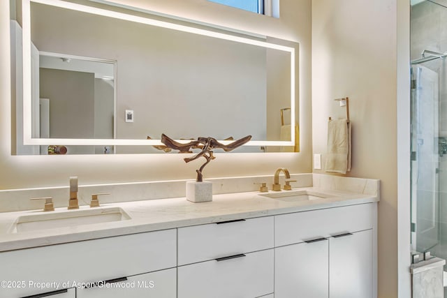 bathroom featuring a shower with door, a sink, and double vanity