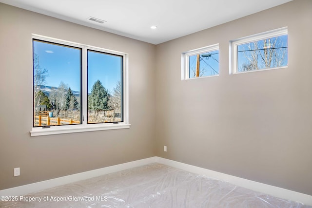 empty room featuring recessed lighting, visible vents, and baseboards