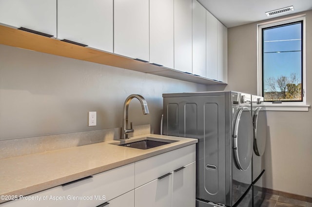 laundry room featuring cabinet space, a sink, visible vents, and separate washer and dryer