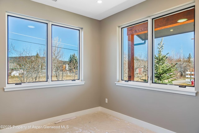 empty room with plenty of natural light and baseboards