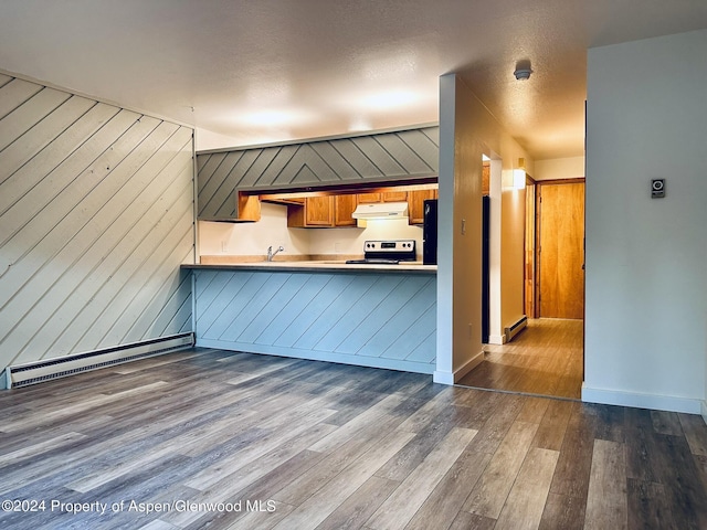 kitchen with baseboard heating, stainless steel range with electric stovetop, wooden walls, dark hardwood / wood-style floors, and kitchen peninsula