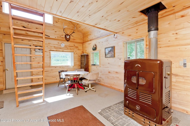 carpeted dining area with wooden walls, wood ceiling, and lofted ceiling