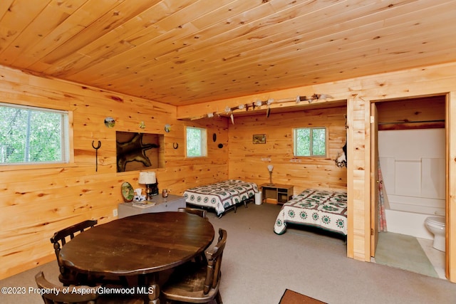 carpeted bedroom with wood walls, wood ceiling, and ensuite bath