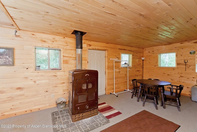 dining room with carpet floors, wood walls, and wood ceiling