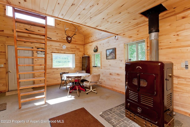 carpeted dining room featuring lofted ceiling, wooden walls, and wood ceiling