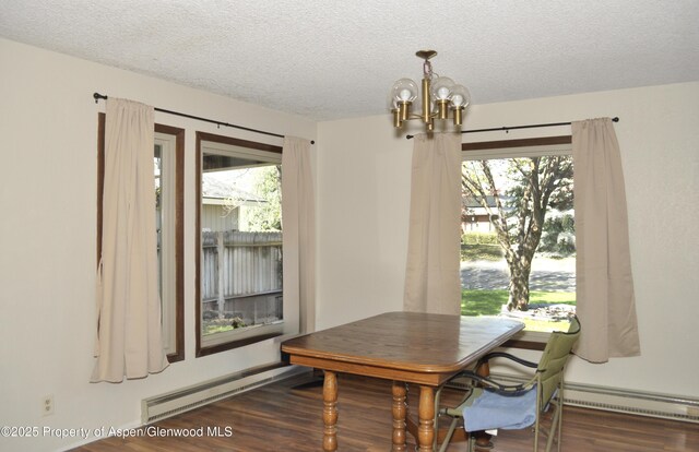 dining area featuring a chandelier, a textured ceiling, a baseboard heating unit, wood finished floors, and healthy amount of natural light