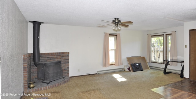 unfurnished living room featuring a baseboard heating unit, a ceiling fan, a textured ceiling, a wood stove, and carpet flooring