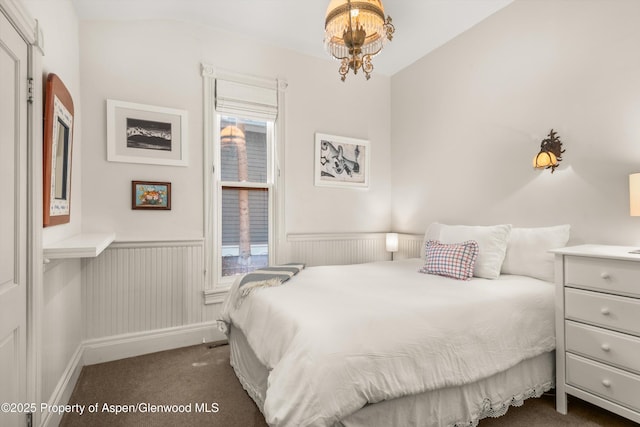 126 W Francis St, Aspen, CO 81611 - bedroom with dark carpet, a wainscoted wall, and a chandelier