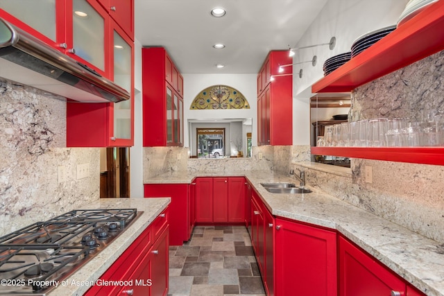 126 W Francis St, Aspen, CO 81611 - kitchen featuring a sink, stainless steel gas cooktop, red cabinets, exhaust hood, and decorative backsplash