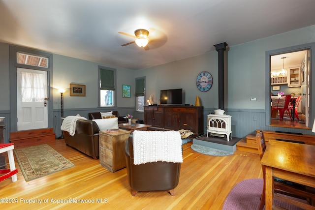 living room with light wood-type flooring, a wood stove, plenty of natural light, and ceiling fan