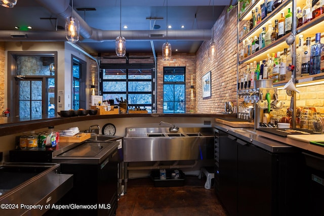 bar with decorative light fixtures, sink, and brick wall