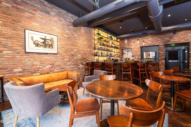 dining space with bar area, a high ceiling, and brick wall