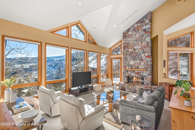 living room featuring a fireplace, high vaulted ceiling, and rail lighting