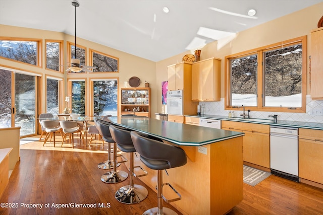 kitchen featuring tasteful backsplash, hanging light fixtures, a kitchen island, and light hardwood / wood-style flooring