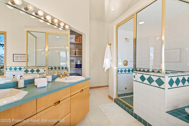 bathroom with a shower with door, vanity, and tile patterned floors