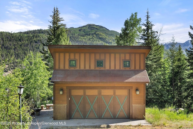 117 Deer Ln, Marble, CO 81623 - view of front of property featuring a mountain view, board and batten siding, a view of trees, an attached garage, and a metal roof