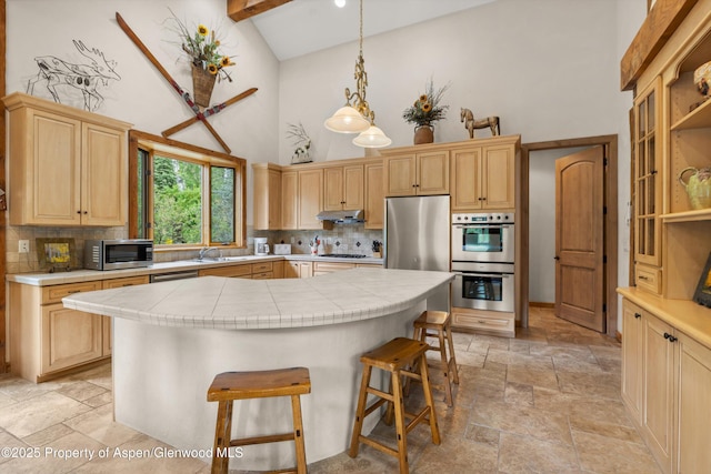 117 Deer Ln, Marble, CO 81623 - kitchen with high vaulted ceiling, stainless steel appliances, stone tile floors, light brown cabinetry, and tile counters