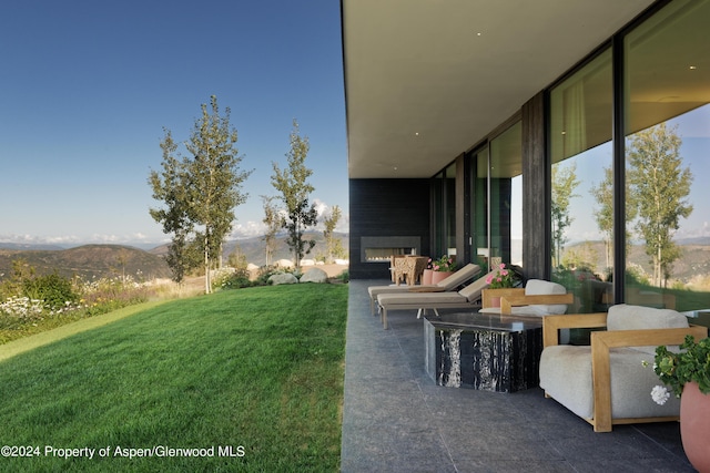 542 Carroll Dr, Aspen, CO 81611 - view of green lawn featuring a patio, a mountain view, and an outdoor living space with a fireplace