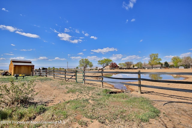 view of yard with an outbuilding, a water view, and a rural view