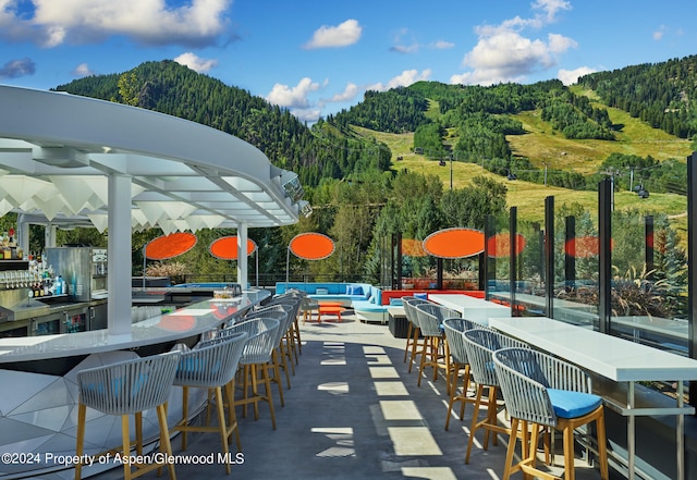 view of patio / terrace with outdoor lounge area, a mountain view, and an outdoor bar