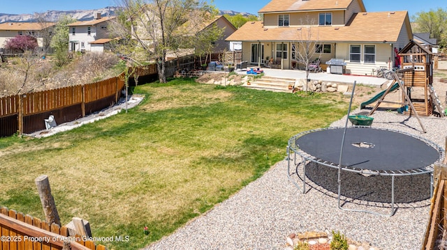 2086 Acacia Ave, Rifle, CO 81650 - fenced backyard featuring a trampoline, a patio area, and a playground