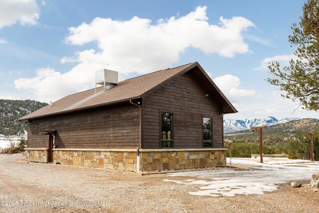 view of property exterior featuring stone siding and a mountain view