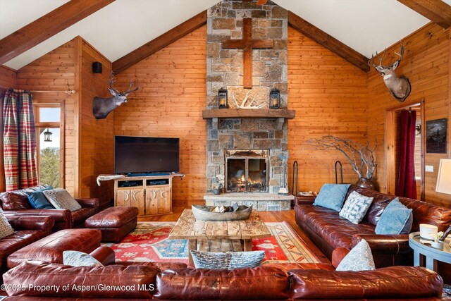 living room with wood walls, beamed ceiling, a fireplace, and wood finished floors