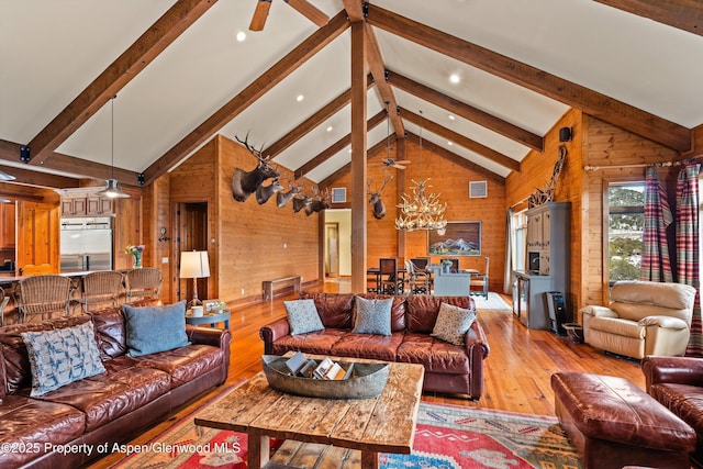 living room with beamed ceiling, high vaulted ceiling, light wood-type flooring, and wooden walls