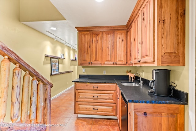 kitchen featuring track lighting, dishwasher, sink, and light tile patterned floors