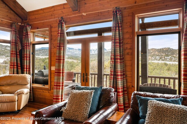 interior space with wood walls, a mountain view, wood finished floors, and french doors