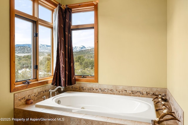 bathroom featuring tiled bath, a mountain view, and a wealth of natural light