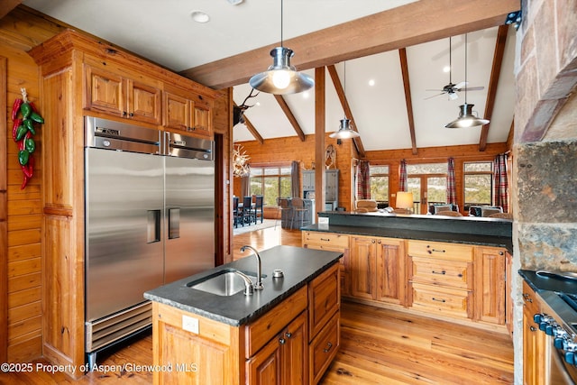 kitchen featuring lofted ceiling with beams, sink, hanging light fixtures, stainless steel built in fridge, and light wood-type flooring