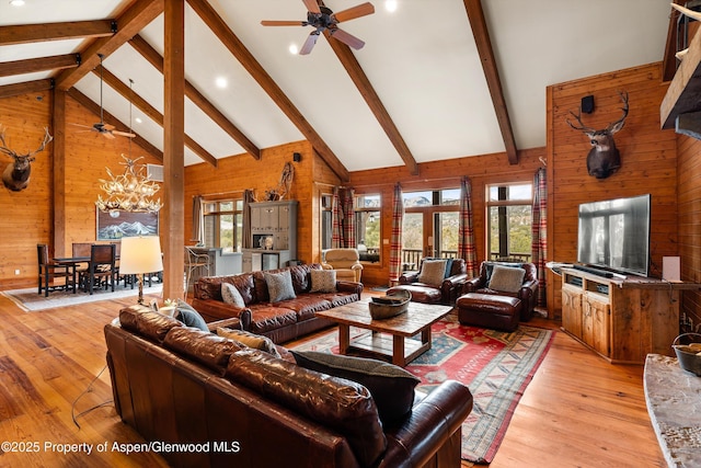 living room featuring a wealth of natural light, high vaulted ceiling, and wood walls