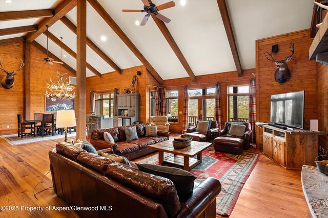 living room with high vaulted ceiling, wood walls, and plenty of natural light