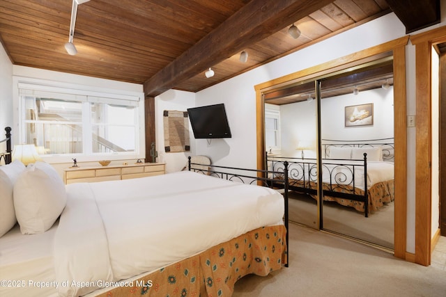 bedroom with beamed ceiling, light colored carpet, wood ceiling, and track lighting