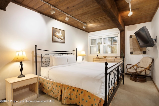 bedroom featuring light carpet, beamed ceiling, rail lighting, and wooden ceiling